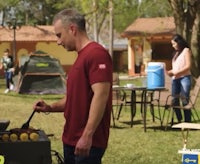 a man is preparing food on a grill in a backyard