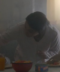 a woman is preparing food in a kitchen with smoke in the background