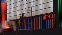 a man standing on a ladder next to a netflix sign