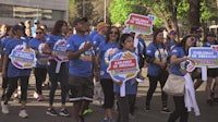 a group of people in blue shirts holding signs