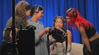 a group of women are sitting in a room with a microphone