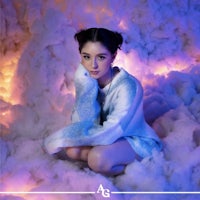 a girl in a blue sweater sitting on a cloud