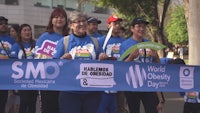 a group of people holding a banner that says world obesity day